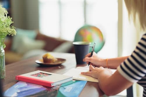 shallow-focus-photography-of-person-in-white-and-black-striped-top-writing-on-white-paper