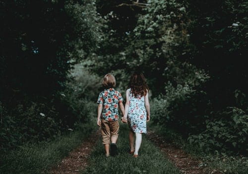 boy-and-girl-walking-hand-in-hand-towards-the-woods