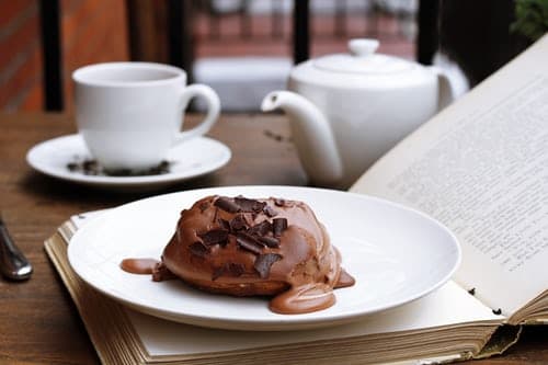 Chocolate-dessert-on-an-open-book-with-a-tea-pot-and-tea-cup-in-the-background