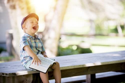 boy-sitting-on-bench-while-holding-a-book