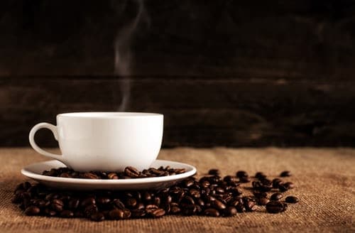 white-ceramic-mug-and-saucer-with-coffee-beans-on-brown-textile