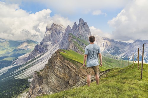 man in blue T-shirt on top of the mountain under the blue sky